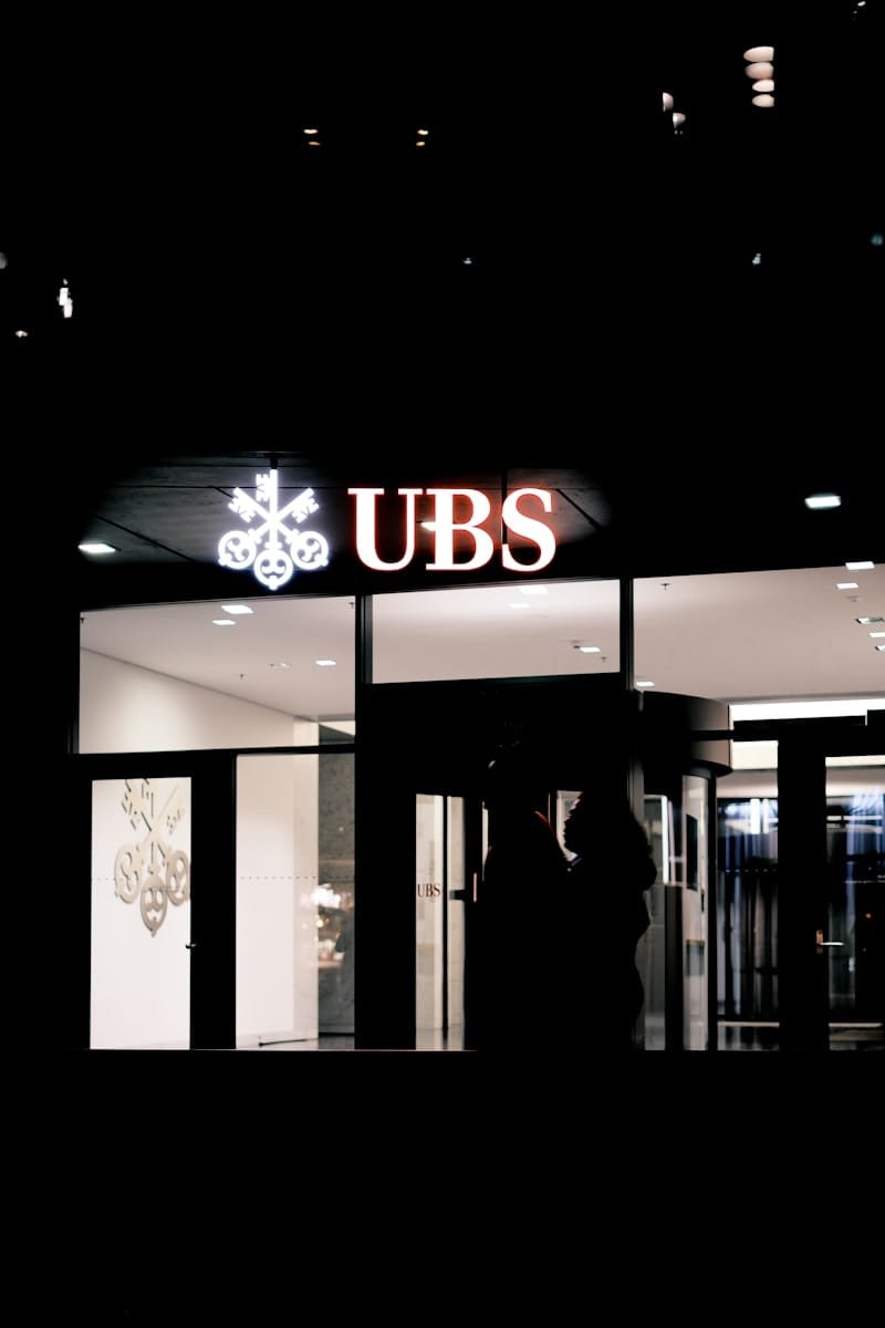 A business professional standing outside UBS Bank building at night, symbolizing Swiss banking accessibility and services for international businesses.